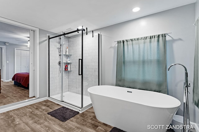 bathroom featuring a freestanding tub, a shower stall, and wood finished floors