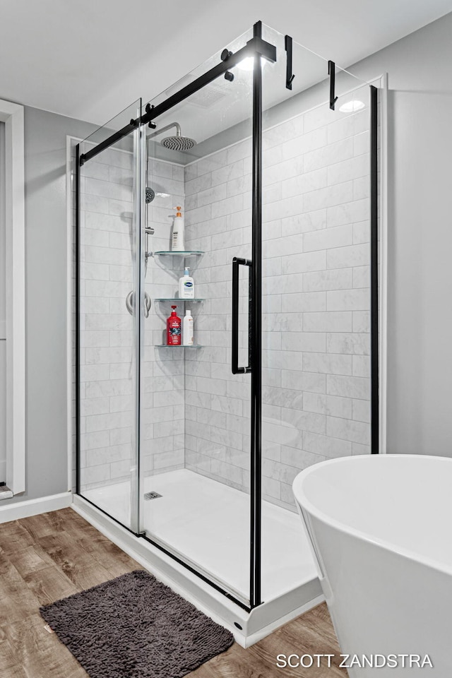 bathroom with a soaking tub, a shower stall, and wood finished floors