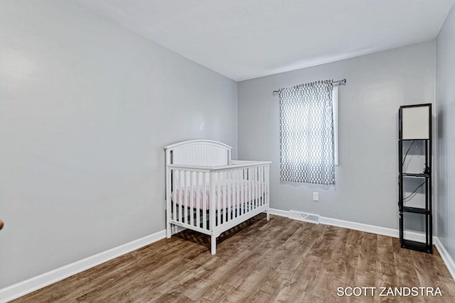 unfurnished bedroom with wood finished floors, visible vents, and baseboards