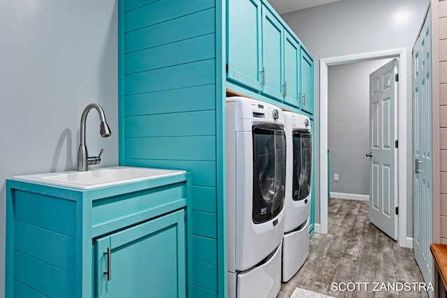 laundry room with cabinet space, a sink, light wood finished floors, and washing machine and clothes dryer