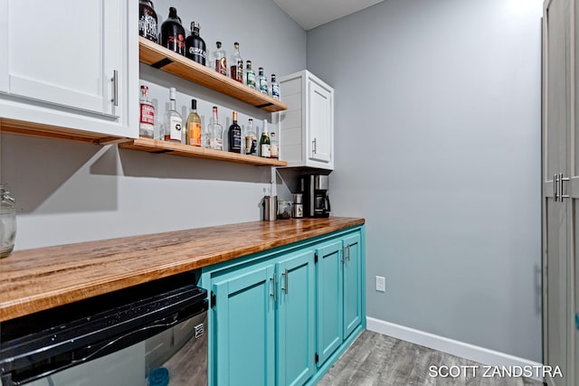 bar featuring beverage cooler, baseboards, light wood-style flooring, and a dry bar