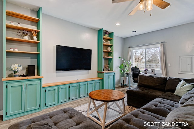 living area with built in features, a ceiling fan, and light wood-style floors