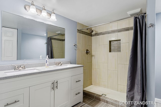 bathroom featuring double vanity, a sink, and tiled shower