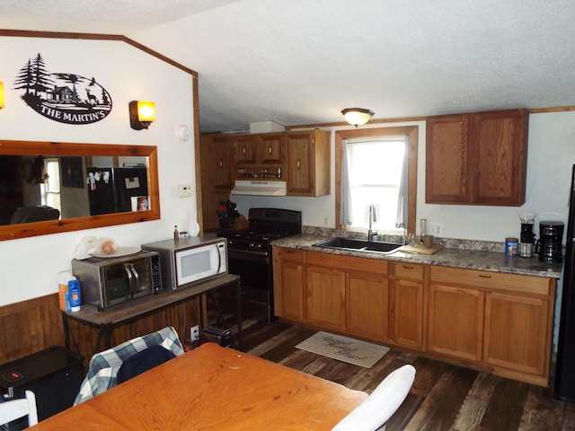 kitchen featuring white microwave, a sink, black gas stove, exhaust hood, and brown cabinets