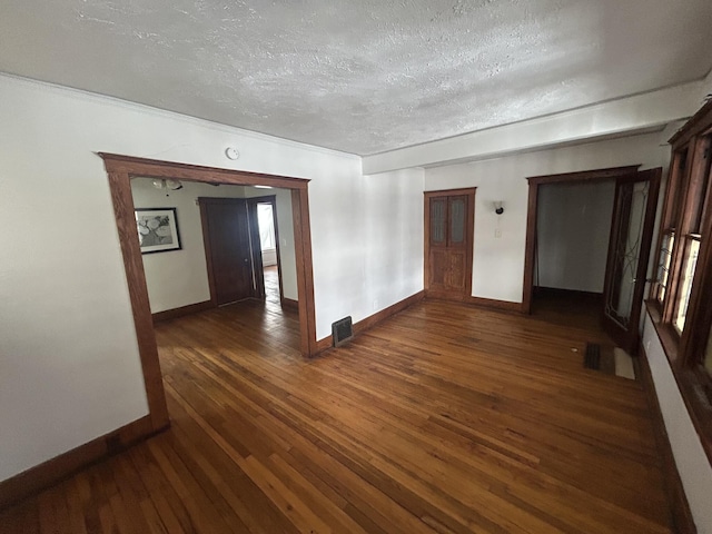 unfurnished room featuring visible vents, a textured ceiling, baseboards, and wood finished floors