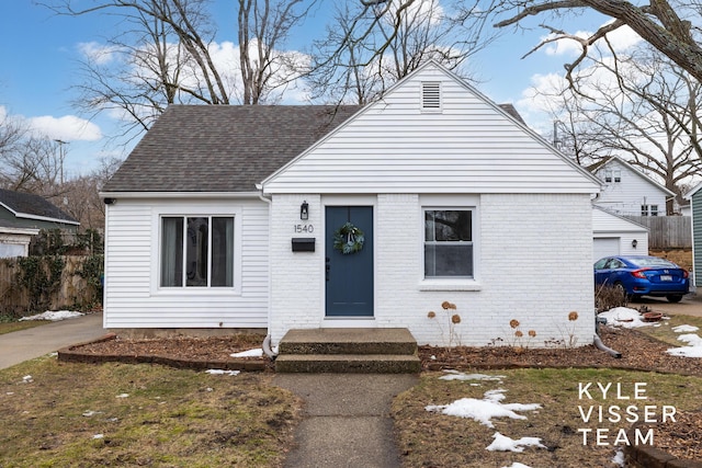 bungalow-style house featuring a shingled roof and brick siding