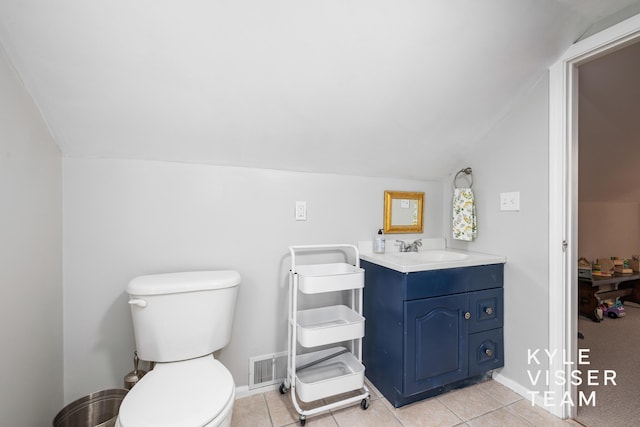 bathroom featuring lofted ceiling, toilet, vanity, baseboards, and tile patterned floors