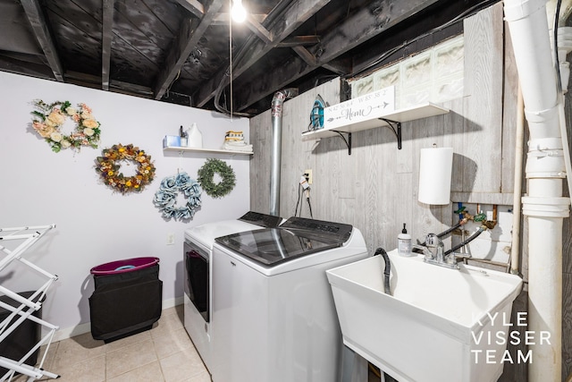 laundry area with light tile patterned floors, a sink, baseboards, and separate washer and dryer