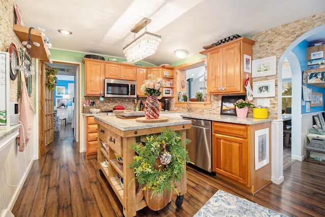 kitchen featuring a sink, stainless steel appliances, arched walkways, and light countertops