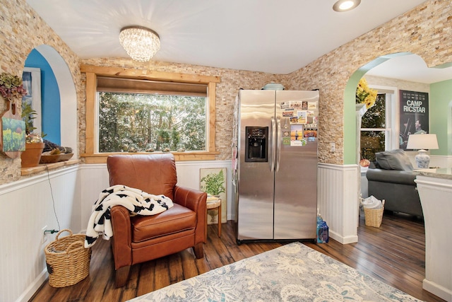 sitting room featuring wood-type flooring, arched walkways, and wainscoting