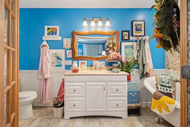 bathroom with toilet, wainscoting, and vanity