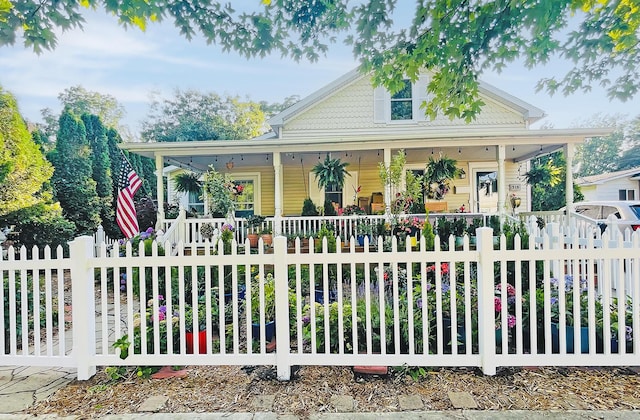 farmhouse with a fenced front yard and covered porch