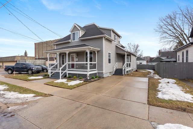 view of front facade featuring concrete driveway, a porch, and fence