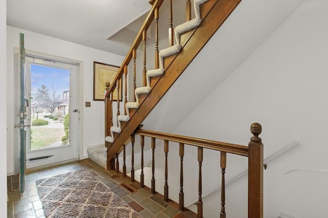 foyer with stone tile floors and stairway