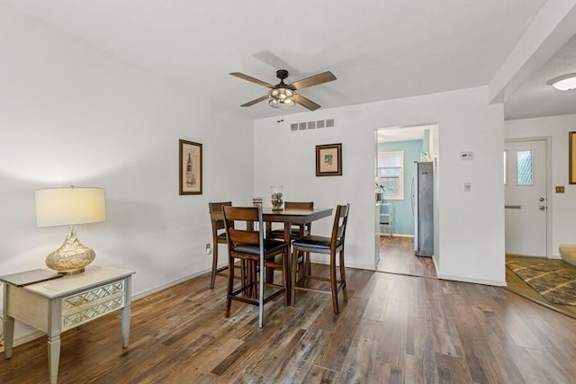 dining space with baseboards, wood finished floors, visible vents, and a ceiling fan