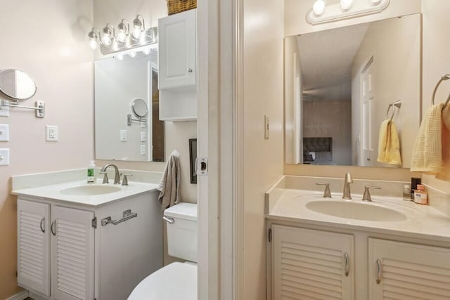 bathroom with toilet, two vanities, and a sink