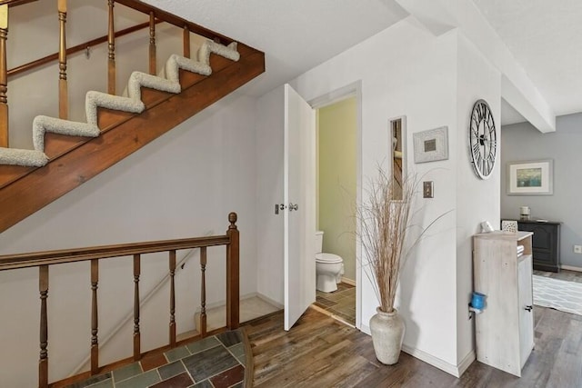 staircase featuring baseboards and wood finished floors