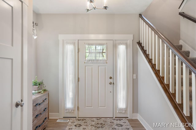 entrance foyer with visible vents, baseboards, wood finished floors, and stairs