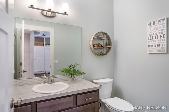 bathroom with backsplash, toilet, and vanity