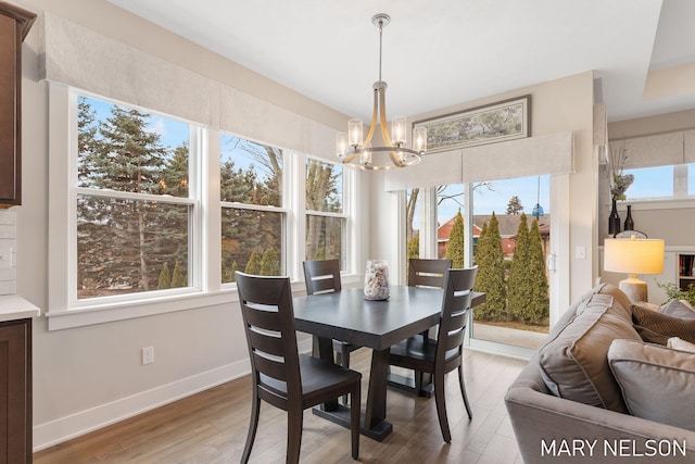 dining area with baseboards, light wood-style floors, and a chandelier