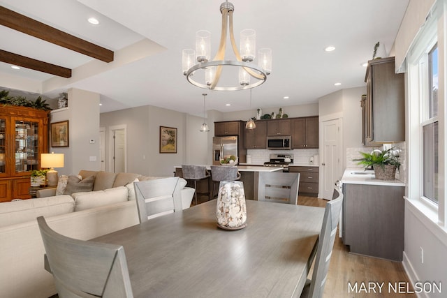 dining room with beamed ceiling, wood finished floors, a wealth of natural light, and a chandelier