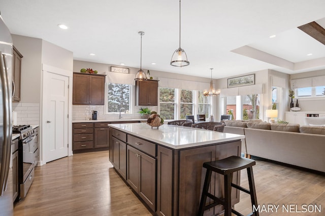 kitchen featuring open floor plan, a breakfast bar area, light wood-type flooring, light countertops, and gas stove