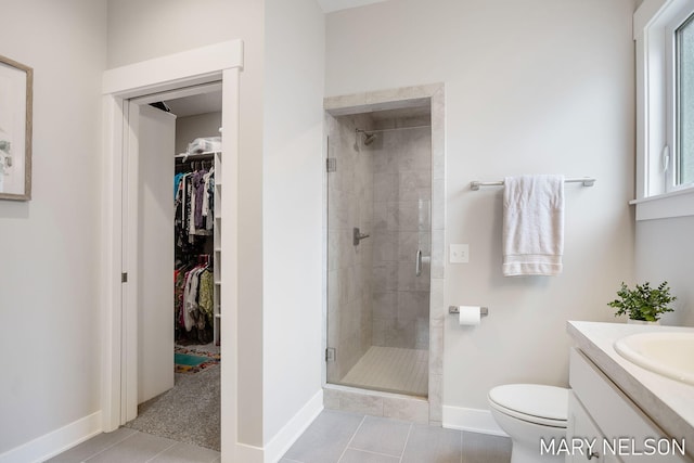 full bathroom with a walk in closet, toilet, a stall shower, tile patterned flooring, and vanity