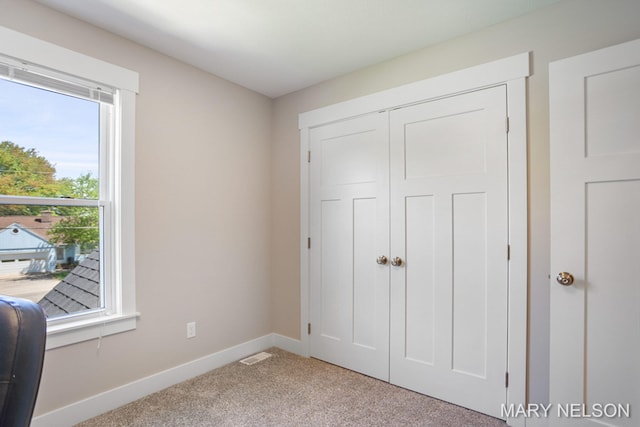 unfurnished bedroom with carpet flooring, visible vents, baseboards, and a closet