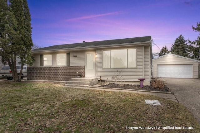 view of front of home with brick siding, a lawn, an outdoor structure, and a detached garage