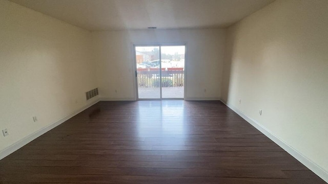 spare room featuring dark wood-style floors, visible vents, and baseboards