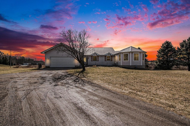 view of front of home featuring an attached garage, metal roof, aphalt driveway, and a lawn