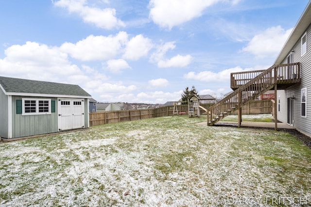 view of yard with an outbuilding, a deck, a fenced backyard, stairs, and a shed