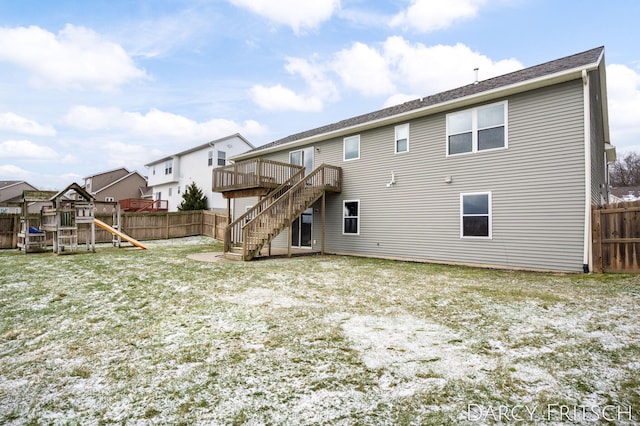 back of property with a playground, a fenced backyard, a yard, stairway, and a wooden deck