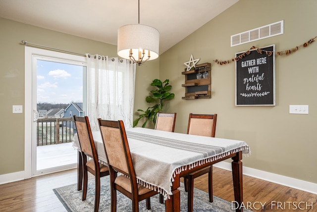 dining space featuring baseboards, wood finished floors, visible vents, and a notable chandelier