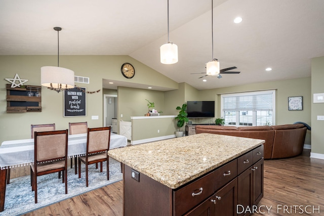 kitchen with wood finished floors, visible vents, open floor plan, vaulted ceiling, and decorative light fixtures