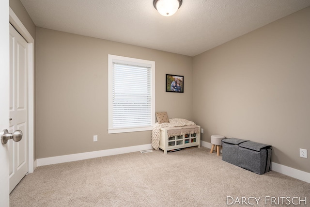 living area featuring a textured ceiling, carpet flooring, visible vents, and baseboards