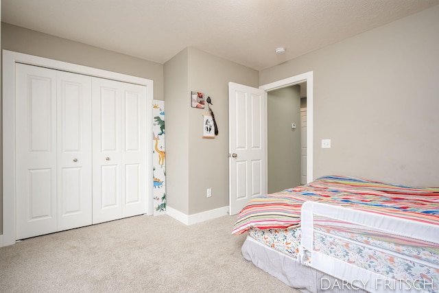 carpeted bedroom with a closet, a textured ceiling, and baseboards