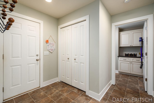 foyer with stone finish floor and baseboards