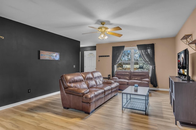 living area featuring ceiling fan, an accent wall, light wood-style flooring, and baseboards