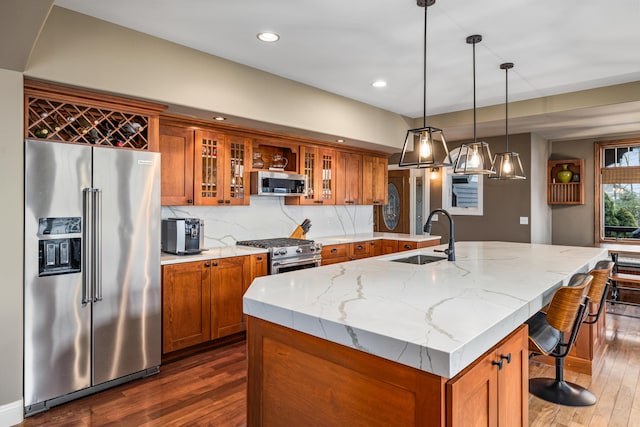 14788 Boom Rd, Spring Lake, MI 49456 - kitchen featuring stainless steel appliances, brown cabinetry, a sink, and light stone counters