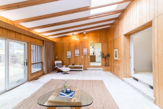 unfurnished room featuring lofted ceiling with skylight, carpet flooring, and wood walls