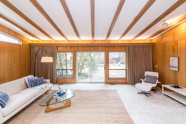 living room featuring wood walls, beamed ceiling, and carpet flooring