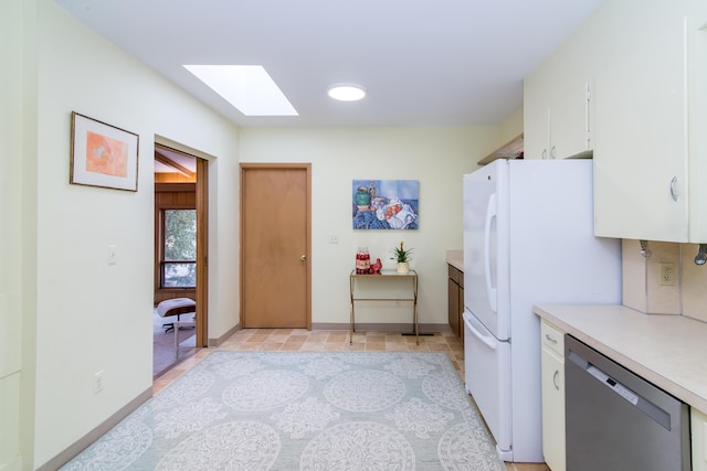 kitchen with a skylight, light countertops, freestanding refrigerator, white cabinets, and dishwasher