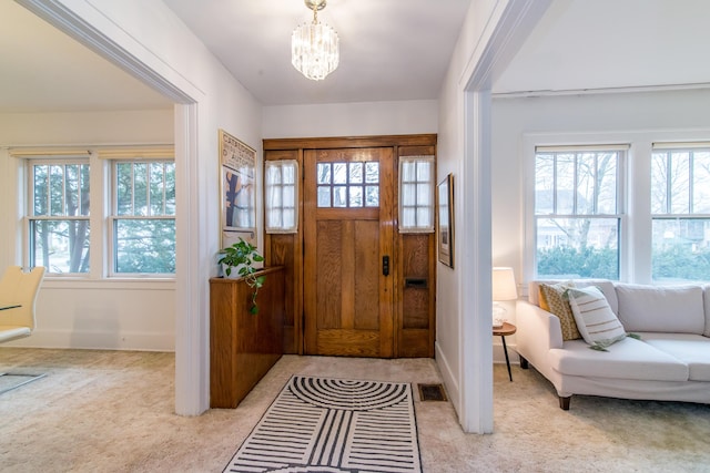 entryway featuring a wealth of natural light, light carpet, a notable chandelier, and visible vents