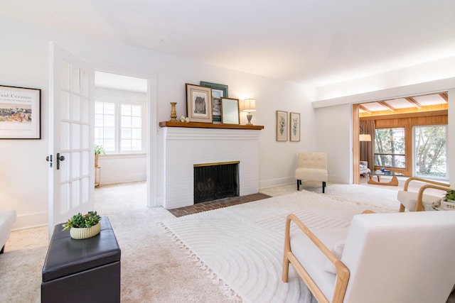 living area featuring baseboards, a fireplace, plenty of natural light, and carpet flooring