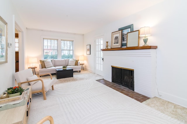 living room featuring a brick fireplace and baseboards