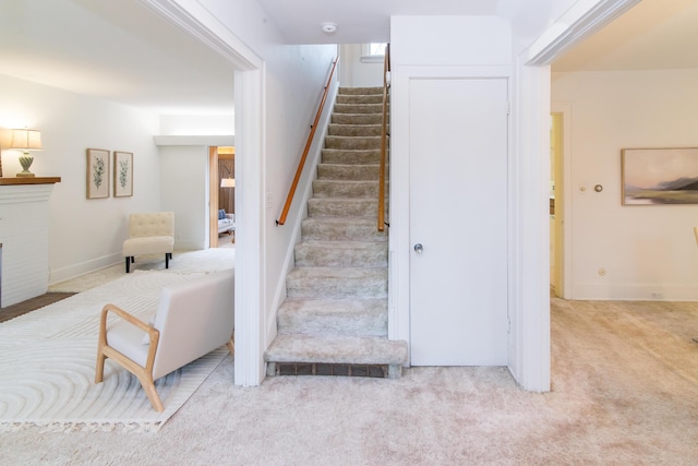 staircase featuring carpet flooring and a fireplace