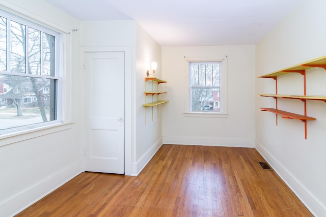 spare room featuring light wood-type flooring, visible vents, and baseboards