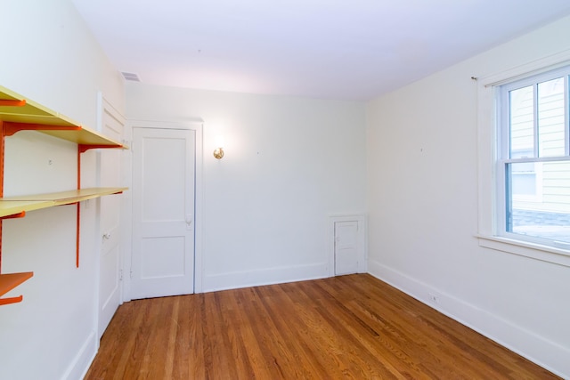 spare room with wood finished floors, visible vents, and baseboards