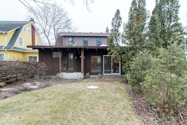 rear view of property with a sunroom, board and batten siding, a chimney, and a lawn